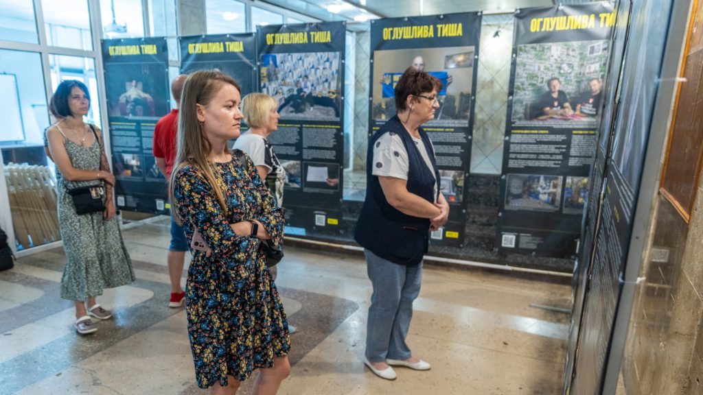 Група з п'яти людей роздивляється плакати з фото та історіями військовополонених та їхніх сімей.